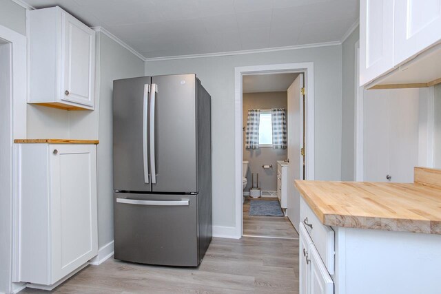 kitchen featuring white cabinets, freestanding refrigerator, ornamental molding, and light wood-style flooring