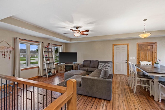 living room featuring baseboards, a ceiling fan, and hardwood / wood-style flooring