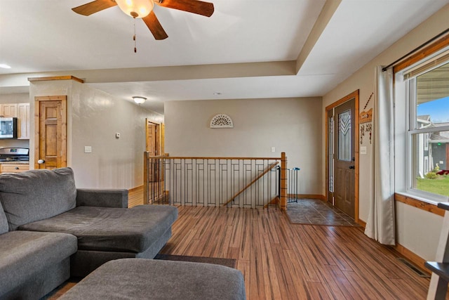 living area featuring baseboards, ceiling fan, and wood finished floors