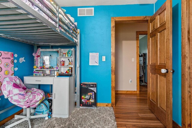 bedroom with baseboards, visible vents, and wood finished floors