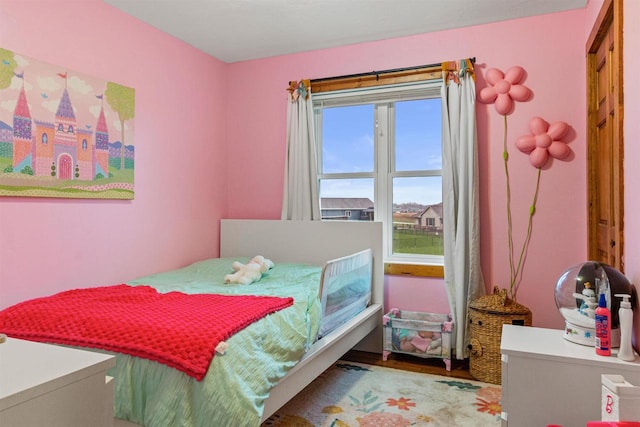 bedroom with wood finished floors and multiple windows