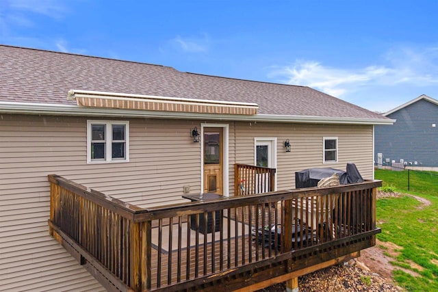 rear view of property with a shingled roof and a wooden deck
