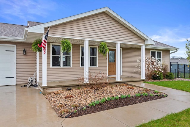 ranch-style house with concrete driveway, a shingled roof, an attached garage, and a porch