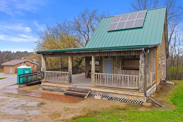 view of front of home featuring a porch, an outbuilding, metal roof, and a standing seam roof