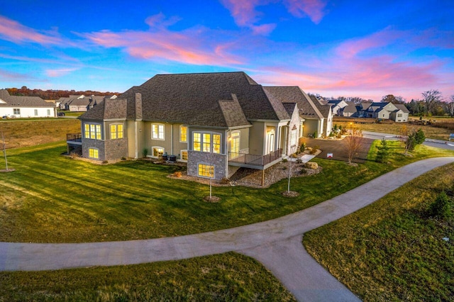 back of house featuring a lawn and a shingled roof