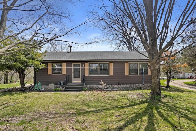 ranch-style home with roof with shingles and a front yard