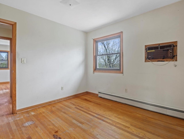 empty room featuring an AC wall unit, a wealth of natural light, baseboard heating, and light wood-style flooring