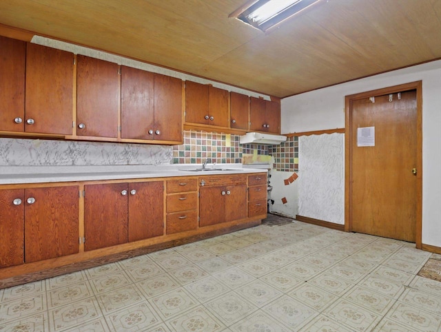 kitchen featuring light floors, light countertops, a sink, and brown cabinets