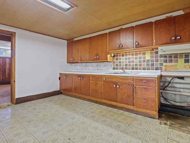 kitchen featuring brown cabinets, baseboards, a sink, and light countertops