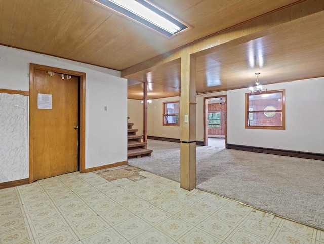 basement featuring carpet floors, a chandelier, stairs, baseboards, and wooden ceiling