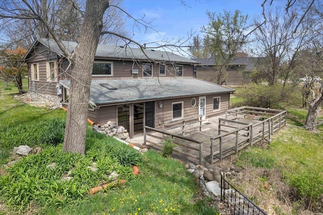 back of property featuring roof with shingles and a vegetable garden