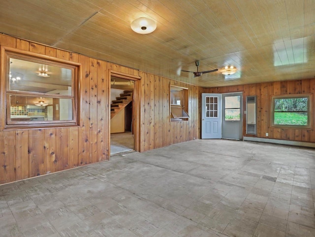 spare room featuring wooden ceiling, baseboard heating, wood walls, and stairs