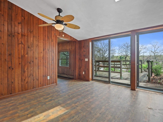empty room featuring wood finished floors, wood walls, ceiling fan, and lofted ceiling
