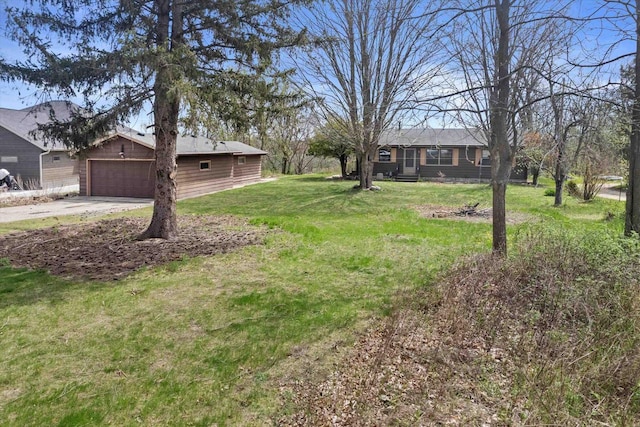 view of yard featuring concrete driveway and a garage