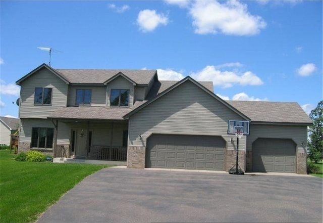 1746 112th St, New Richmond, WI 54017 - view of front of house with an attached garage, a porch, asphalt driveway, and a front lawn