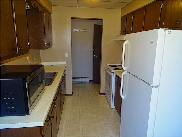 kitchen featuring white appliances, light floors, baseboard heating, light countertops, and a sink