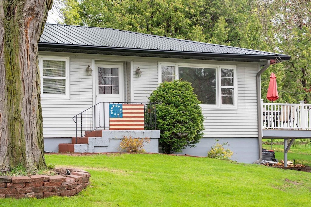 view of front facade featuring a deck, metal roof, and a front lawn