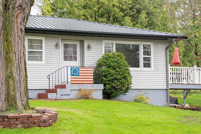 view of front facade featuring a deck, metal roof, and a front lawn