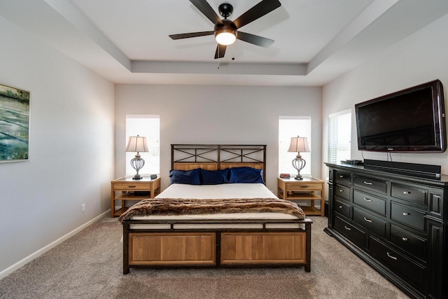 bedroom featuring a tray ceiling, dark carpet, baseboards, and ceiling fan