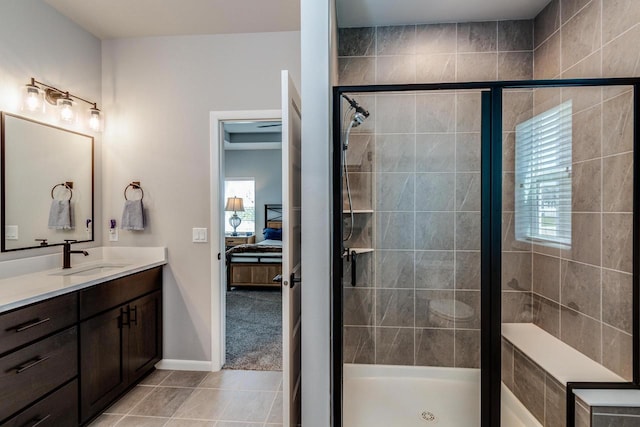 ensuite bathroom featuring a stall shower, vanity, tile patterned floors, and baseboards
