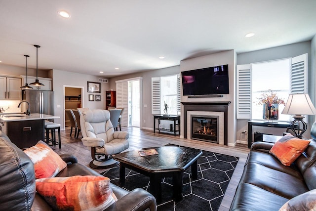 living area with wood finished floors, recessed lighting, baseboards, and a glass covered fireplace