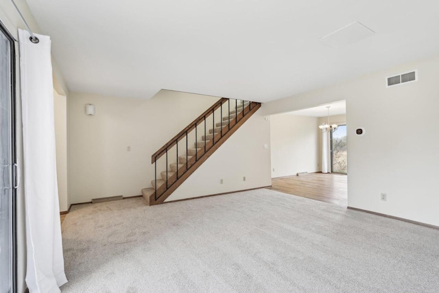 unfurnished living room featuring carpet floors, baseboards, visible vents, and stairway