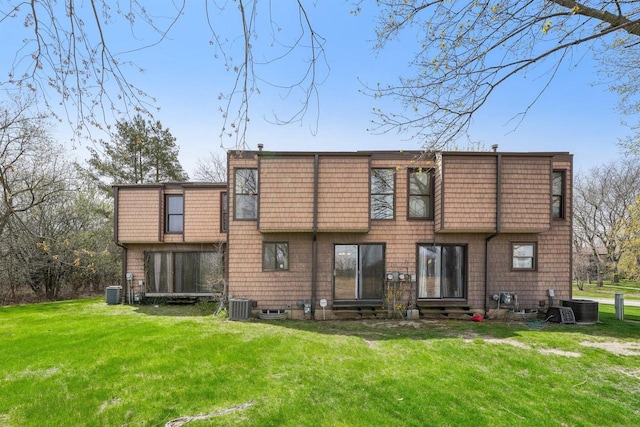 rear view of house featuring central air condition unit, a lawn, and entry steps