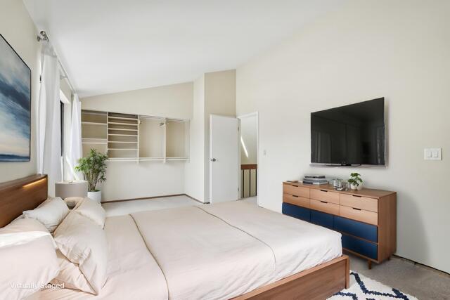 carpeted bedroom with lofted ceiling and a closet