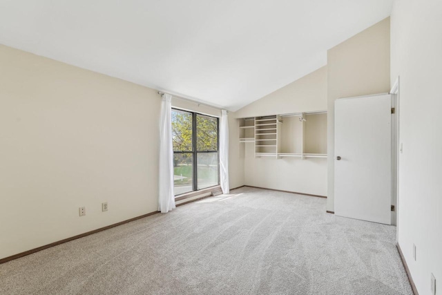 carpeted empty room featuring baseboards and high vaulted ceiling