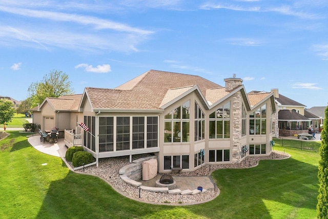 rear view of house featuring a sunroom, a patio area, an outdoor fire pit, and a lawn
