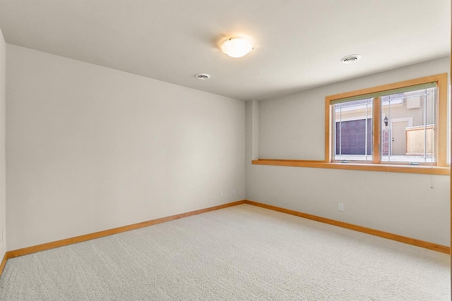 unfurnished room featuring baseboards and light carpet