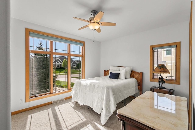 carpeted bedroom with multiple windows, baseboards, and ceiling fan