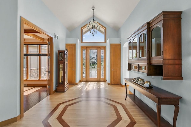 foyer with healthy amount of natural light, a chandelier, vaulted ceiling, light wood-style floors, and baseboards