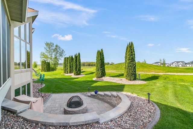 view of green lawn featuring an outdoor fire pit and a patio