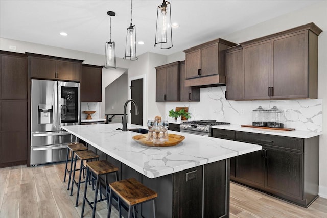 N59W27328 Autumn Ct, Lisbon, WI 53089 - kitchen with appliances with stainless steel finishes, light stone countertops, light wood-type flooring, a sink, and a breakfast bar