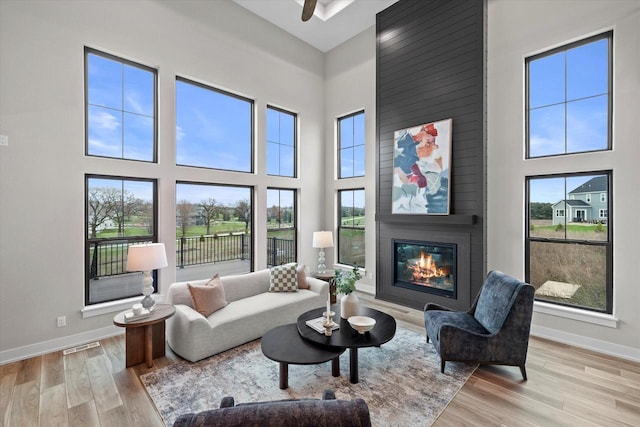 N59W27328 Autumn Ct, Lisbon, WI 53089 - living room featuring light wood-style floors, a large fireplace, baseboards, and a towering ceiling