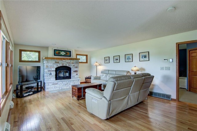 1897 Breezy Bay Rd, Balsam Lake, WI 54810 - living area with visible vents, a textured ceiling, light wood finished floors, and a stone fireplace