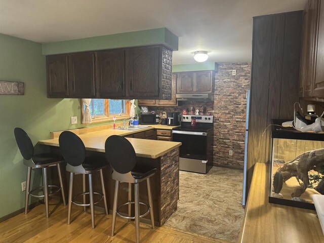 266 Forest St, Berlin, WI 54926 - kitchen featuring stainless steel electric range oven, black microwave, a sink, a peninsula, and under cabinet range hood
