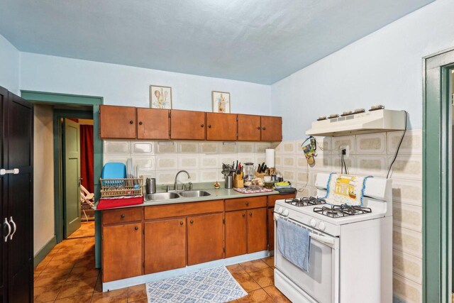 3025 W Pierce St, Milwaukee, WI 53215 - kitchen with a sink, light countertops, brown cabinetry, under cabinet range hood, and white range with gas cooktop