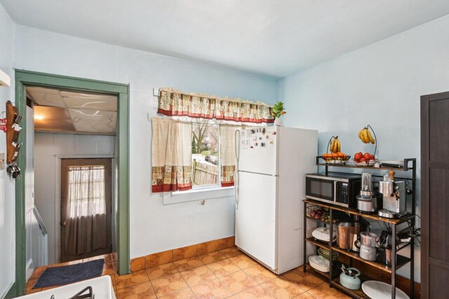 3025 W Pierce St, Milwaukee, WI 53215 - kitchen with freestanding refrigerator, light tile patterned flooring, stainless steel microwave, and baseboards