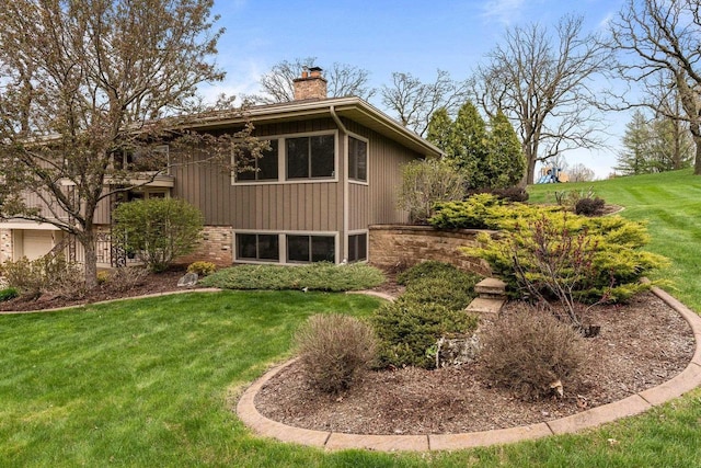 back of house with brick siding, a chimney, and a lawn