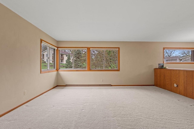 empty room with carpet, baseboards, and a baseboard heating unit