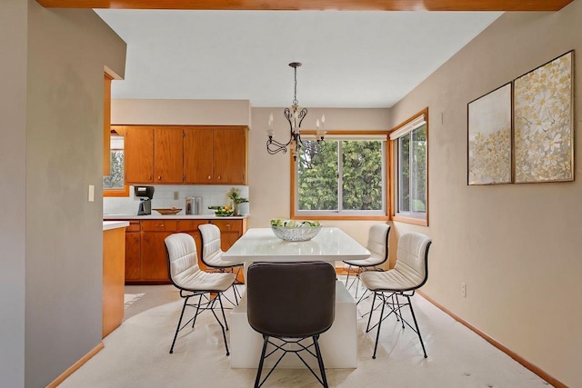 dining space with light colored carpet, an inviting chandelier, and baseboards