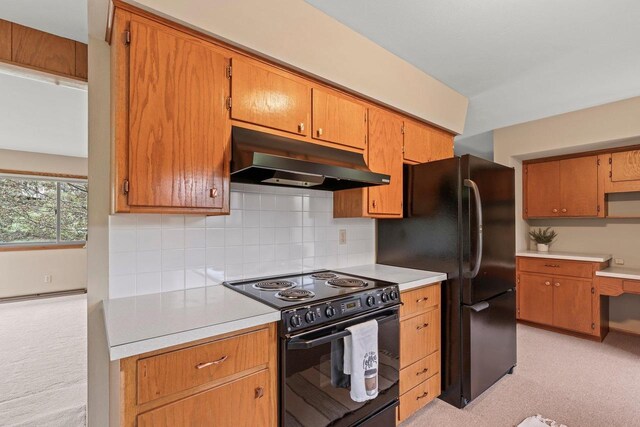 kitchen with under cabinet range hood, black appliances, light carpet, light countertops, and tasteful backsplash