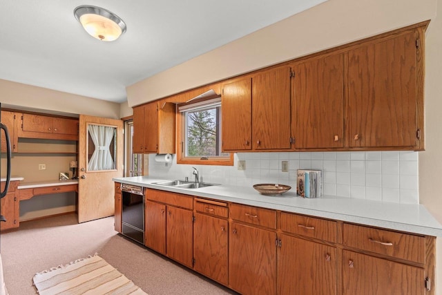 kitchen featuring a sink, black dishwasher, brown cabinetry, backsplash, and light countertops