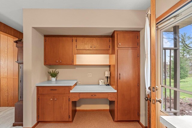 interior space featuring built in desk, light countertops, and brown cabinetry