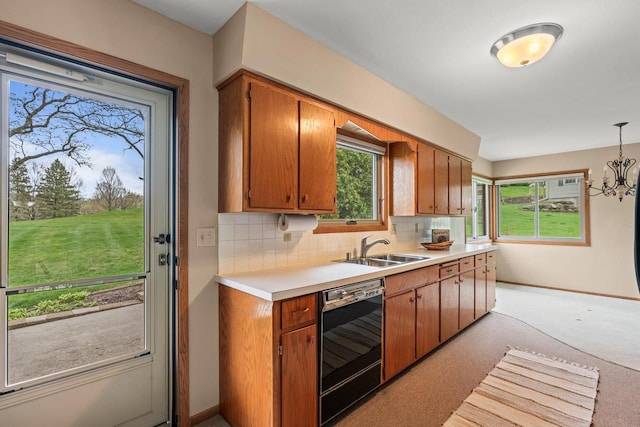 kitchen featuring a sink, tasteful backsplash, dishwasher, light countertops, and baseboards