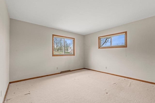spare room featuring carpet, visible vents, baseboards, and a healthy amount of sunlight