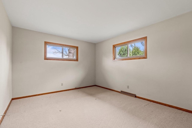 carpeted spare room with visible vents and baseboards