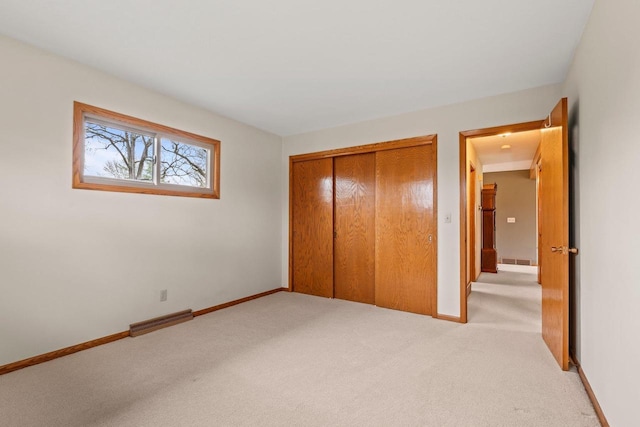 unfurnished bedroom featuring baseboards, a closet, visible vents, and light colored carpet